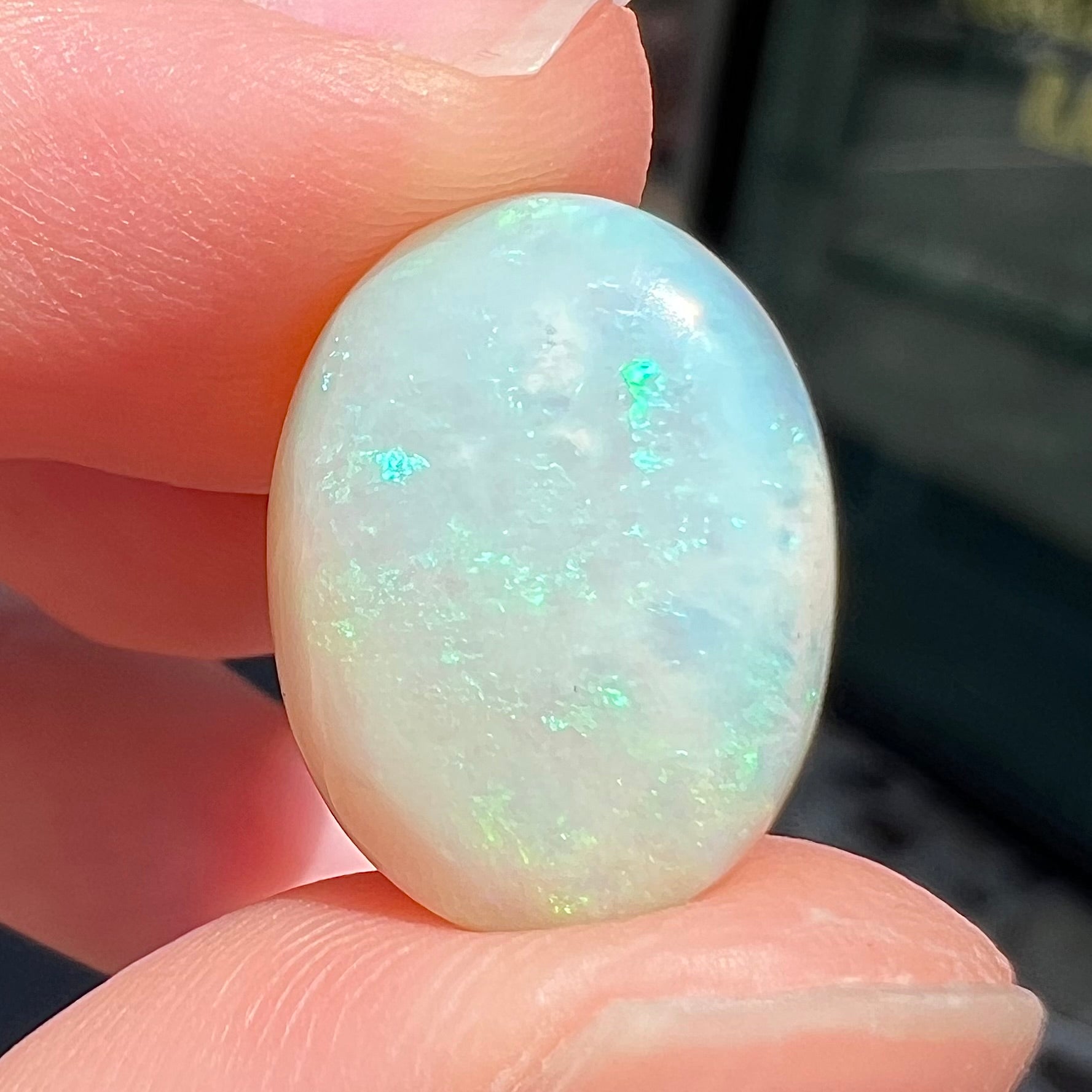 An oval cabochon cut white opal stone from Coober Pedy, Australia.  The opal has subtle colors of green and blue.