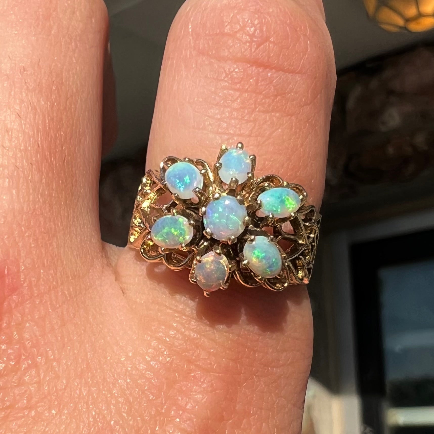 A vintage, 1950's style opal cluster ring cast in yellow gold with a heart shaped filigree design.