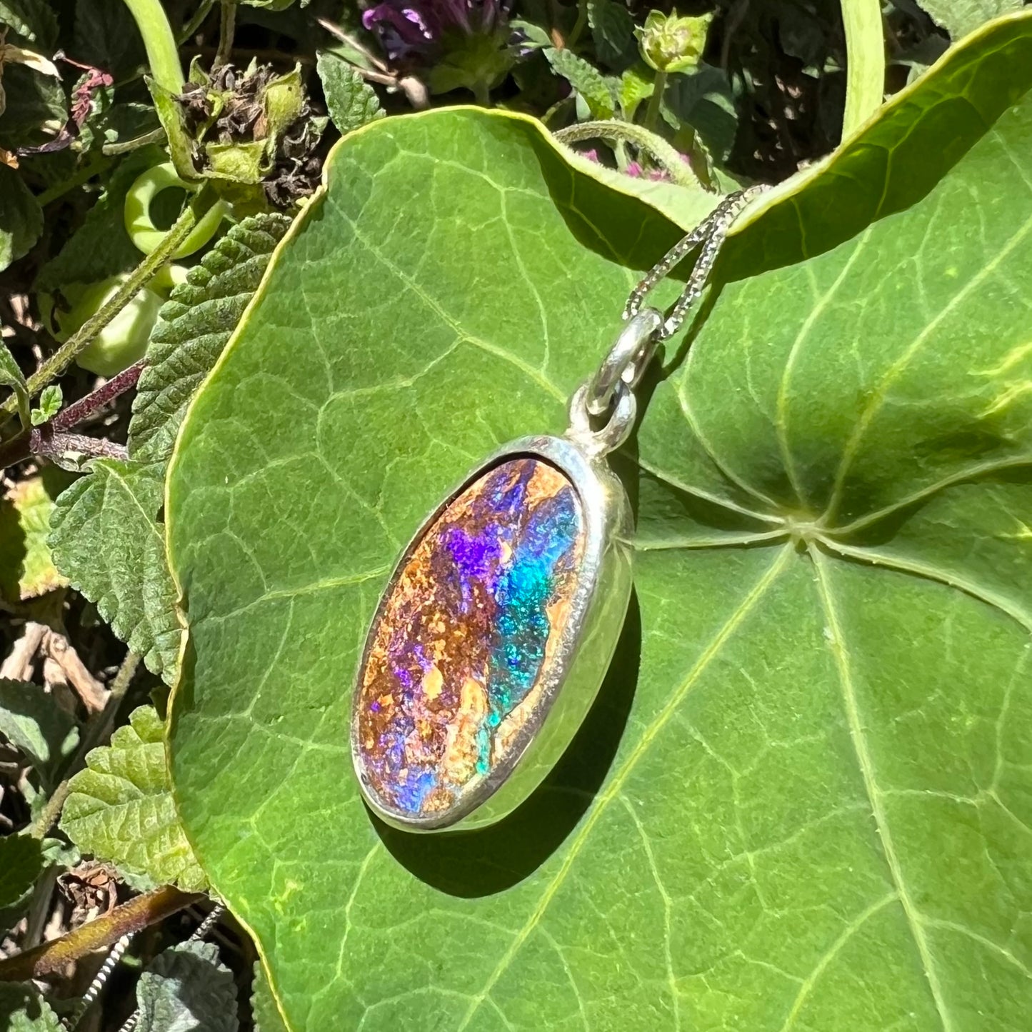 A handmade sterling silver pendant bezel set with an oval cut pipe boulder opal stone.