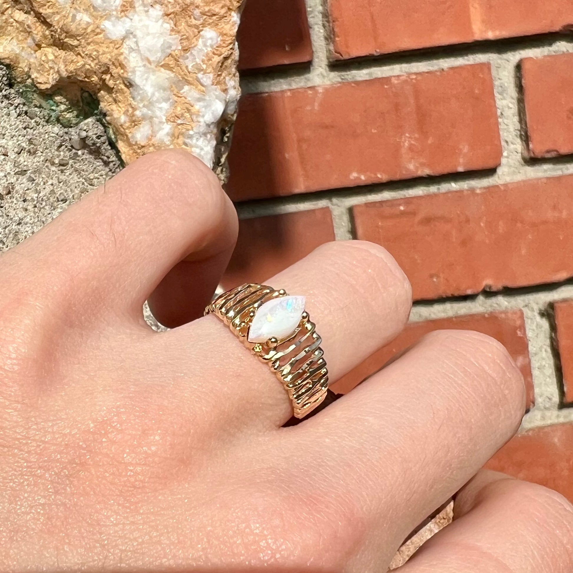 A ladies' yellow gold diamond-cut ring prong set with a natural, marquise cut white opal stone.