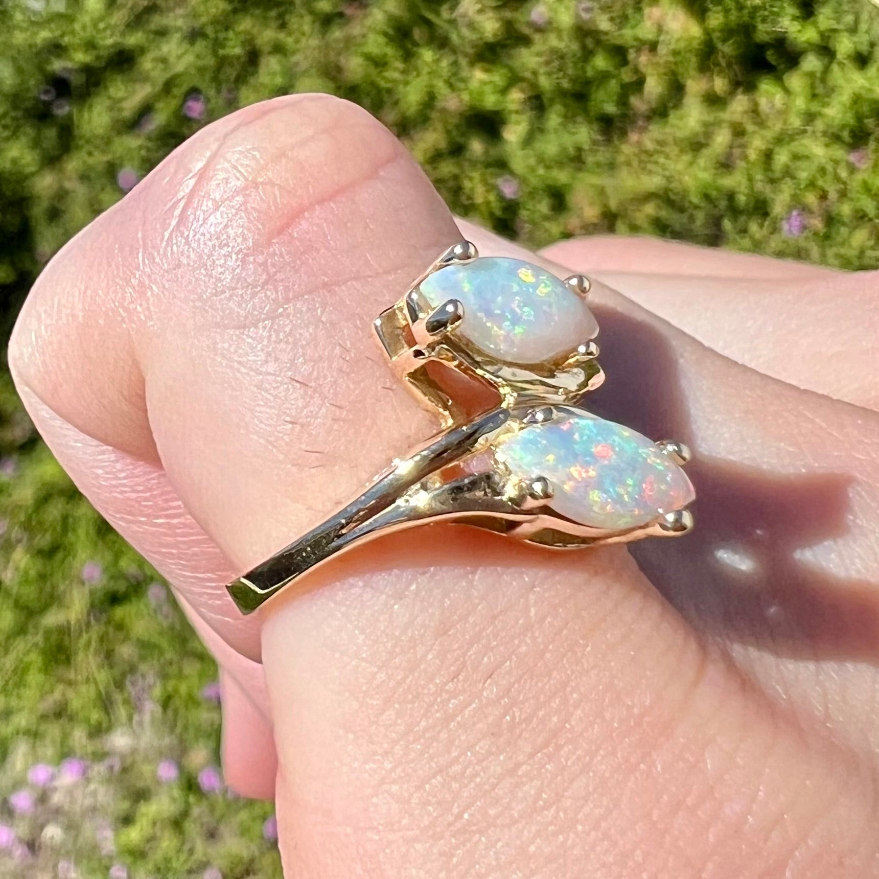 A yellow gold ring mounted with two prong-set marquise cut opal cabochons.