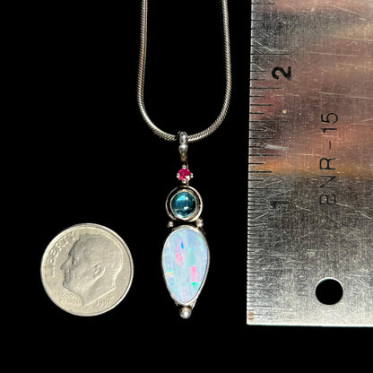 A sterling silver necklace shaped like a child, mounted with an opal doublet, a ruby, and a blue piece of glass.