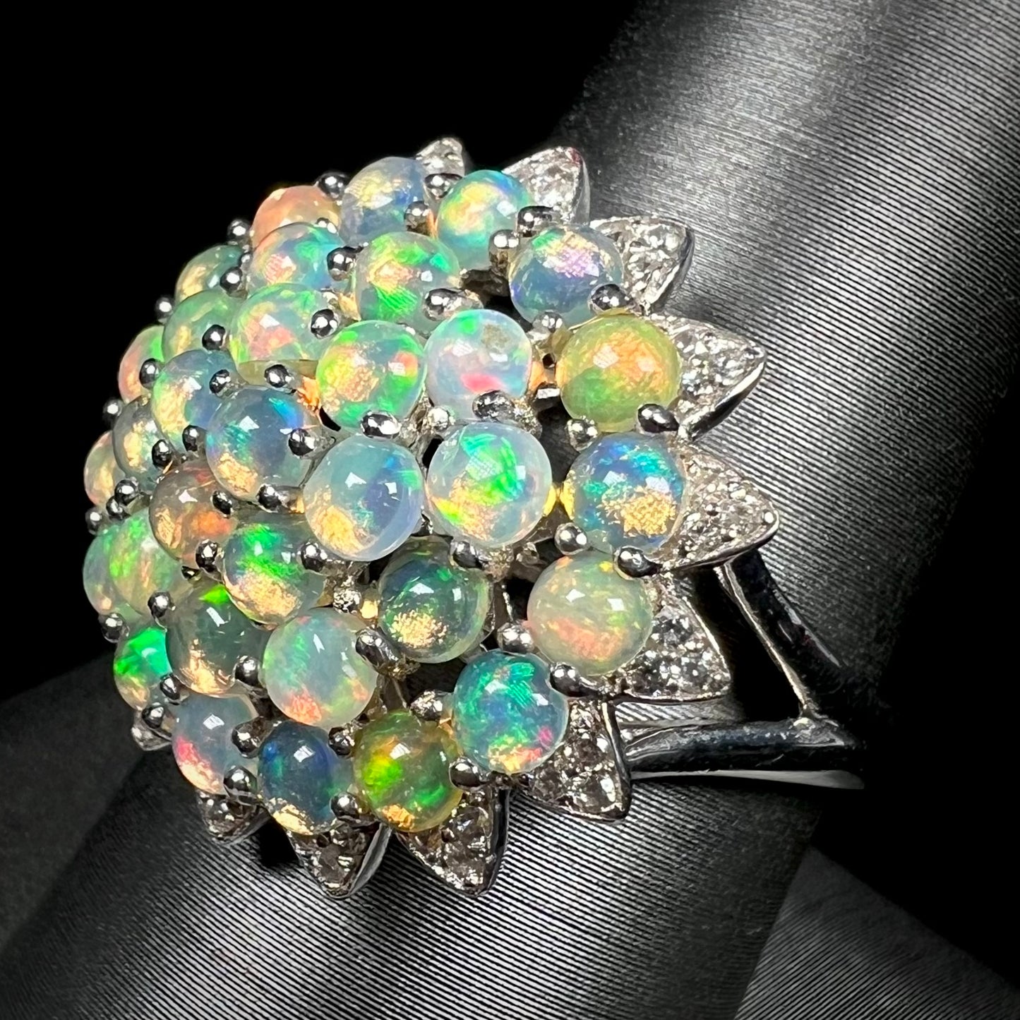 A sterling silver cluster flower ring mounted with 33 round Ethiopian fire opals.