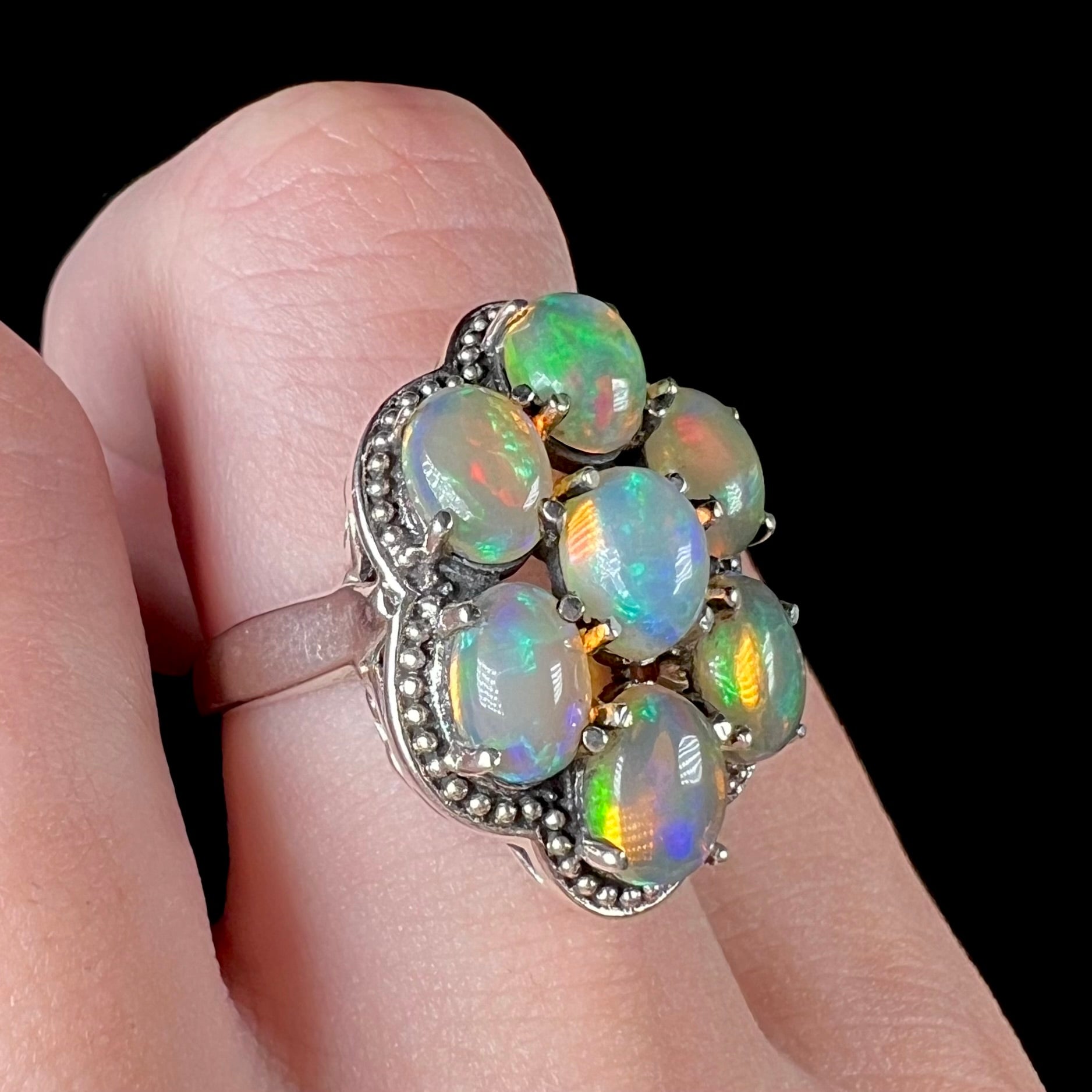 A sterling silver cluster ring prong-set with seven green Ethiopian fire opals.