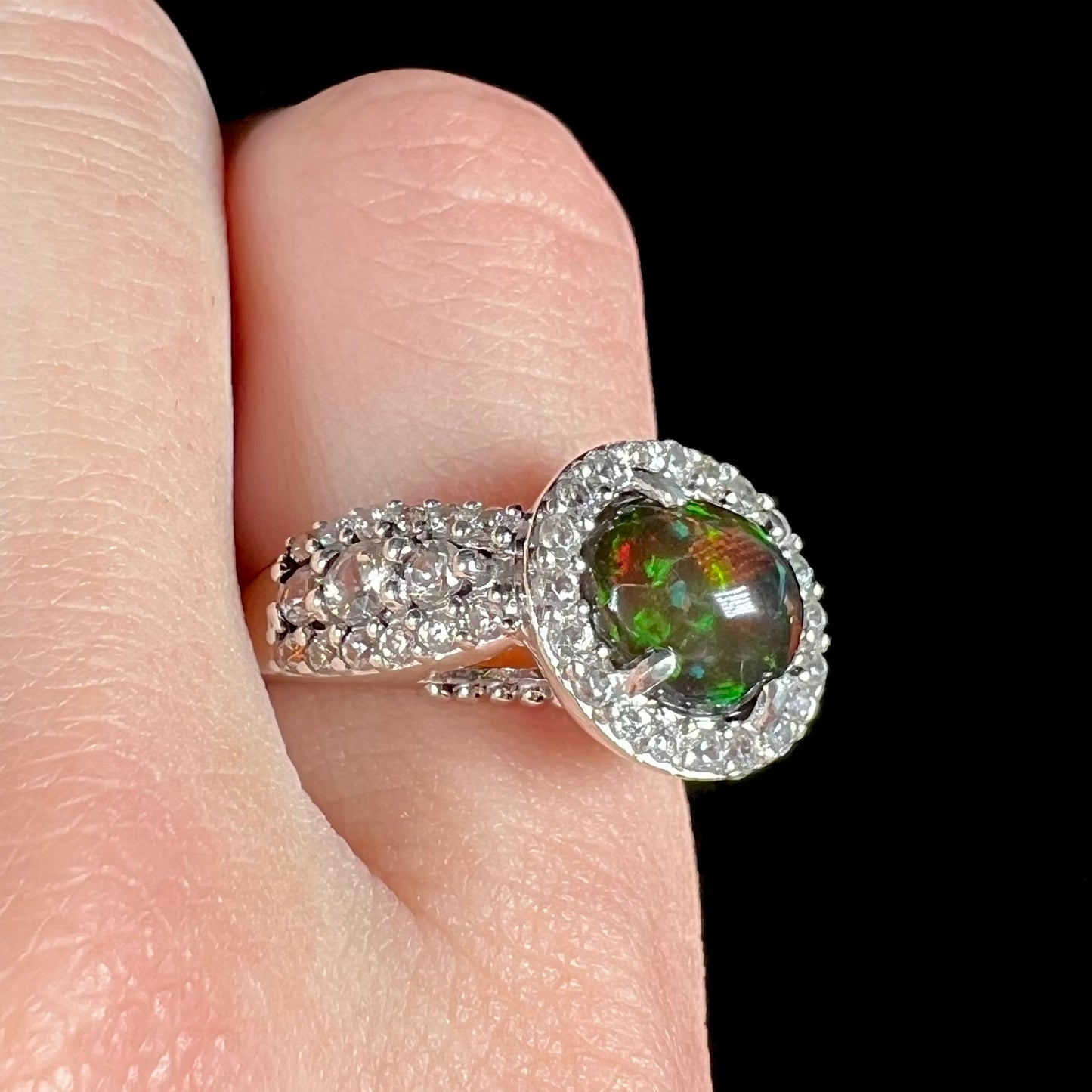 A CZ-accented sterling silver halo ring mounted with a smoked Ethiopian fire opal.  The opal plays green, red, and blue colors.