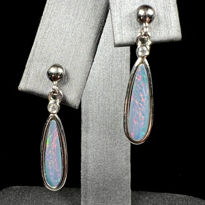 A pair of sterling silver, pear shaped opal doublet dangle earrings.  The opals have a gray body tone with red fire.