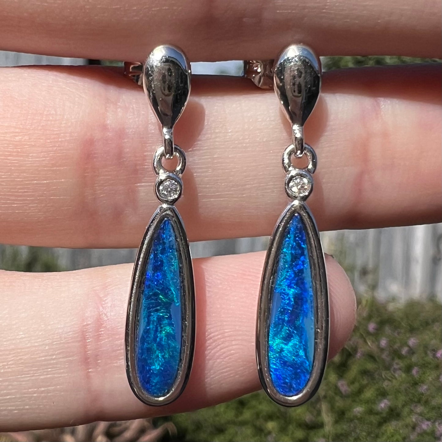 A pair of sterling silver dangle earrings mounted with pear shaped black opal doublets.