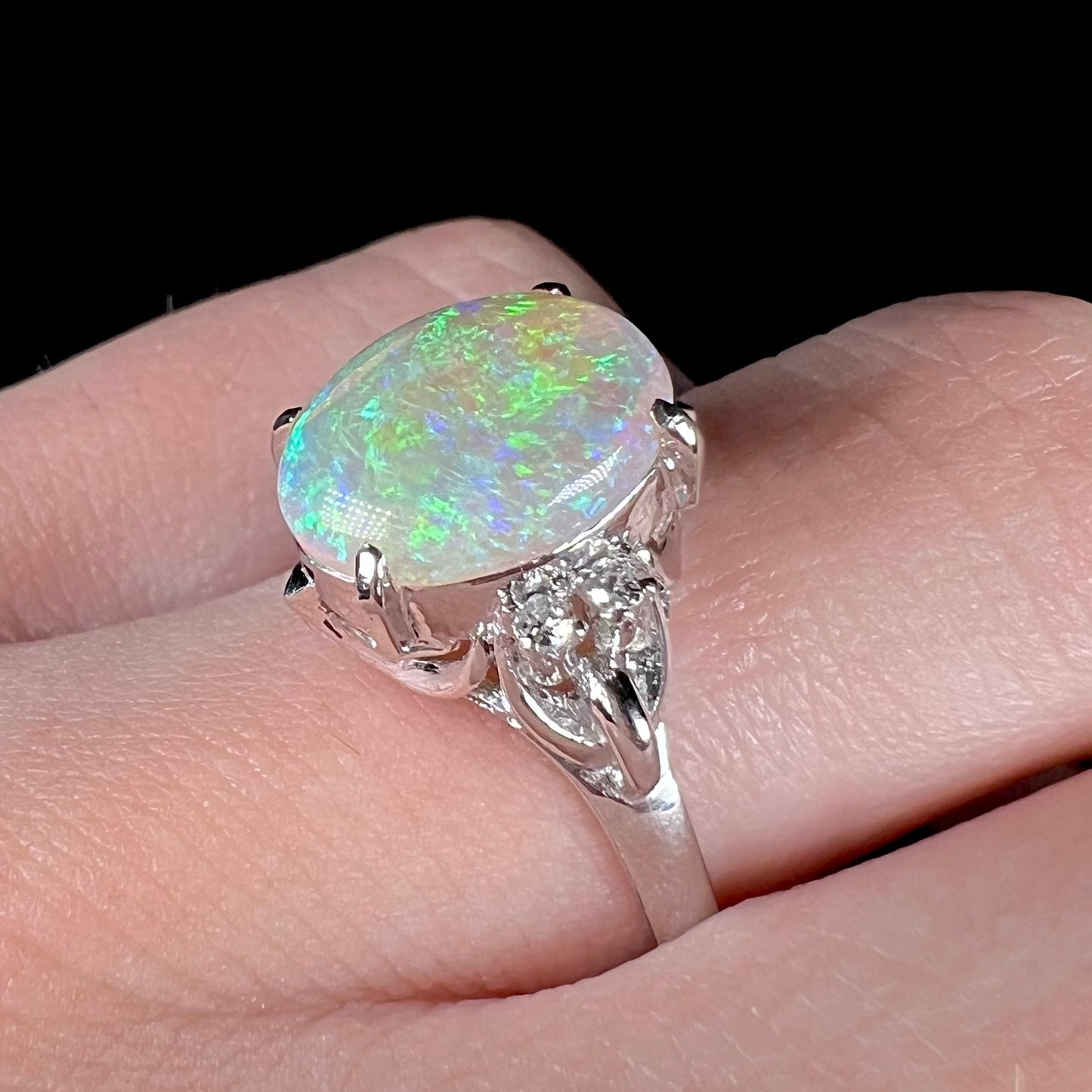 An Australian crystal opal and diamond engagement ring set in a platinum filigree mounting.  The opal plays green/blue colors and has a crack.