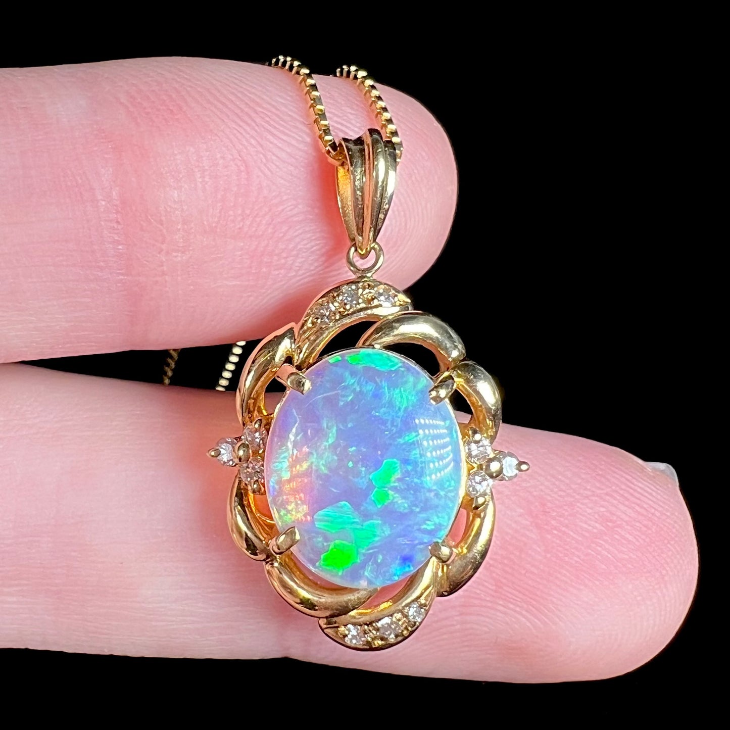 An 18 karat yellow gold diamond-accented necklace mounted with a green and blue Lightning Ridge crystal opal.