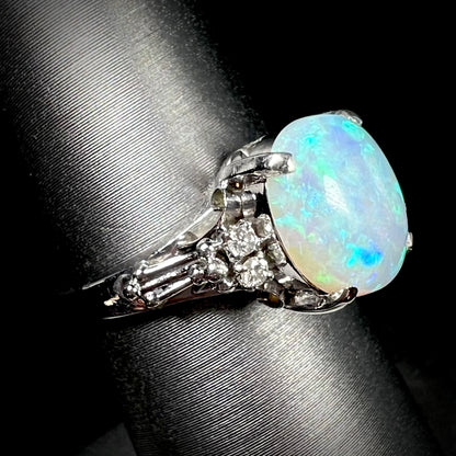 A platinum filigree ring mounted with a blue-green crystal opal and diamond accents.