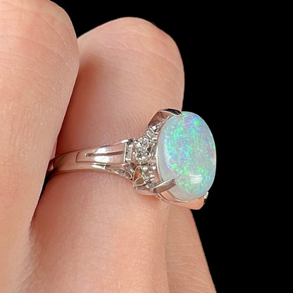 A platinum filigree opal engagement ring set with diamond accents.  The opal has green-blue colors.