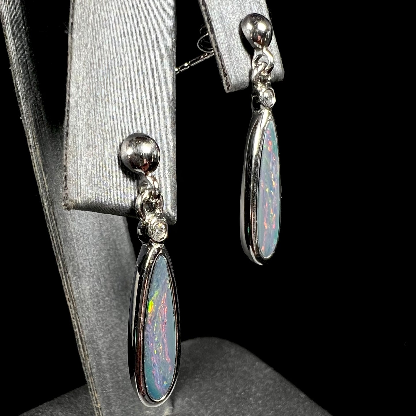 A pair of sterling silver, pear shaped opal doublet dangle earrings.  The opals have a gray body tone with red fire.