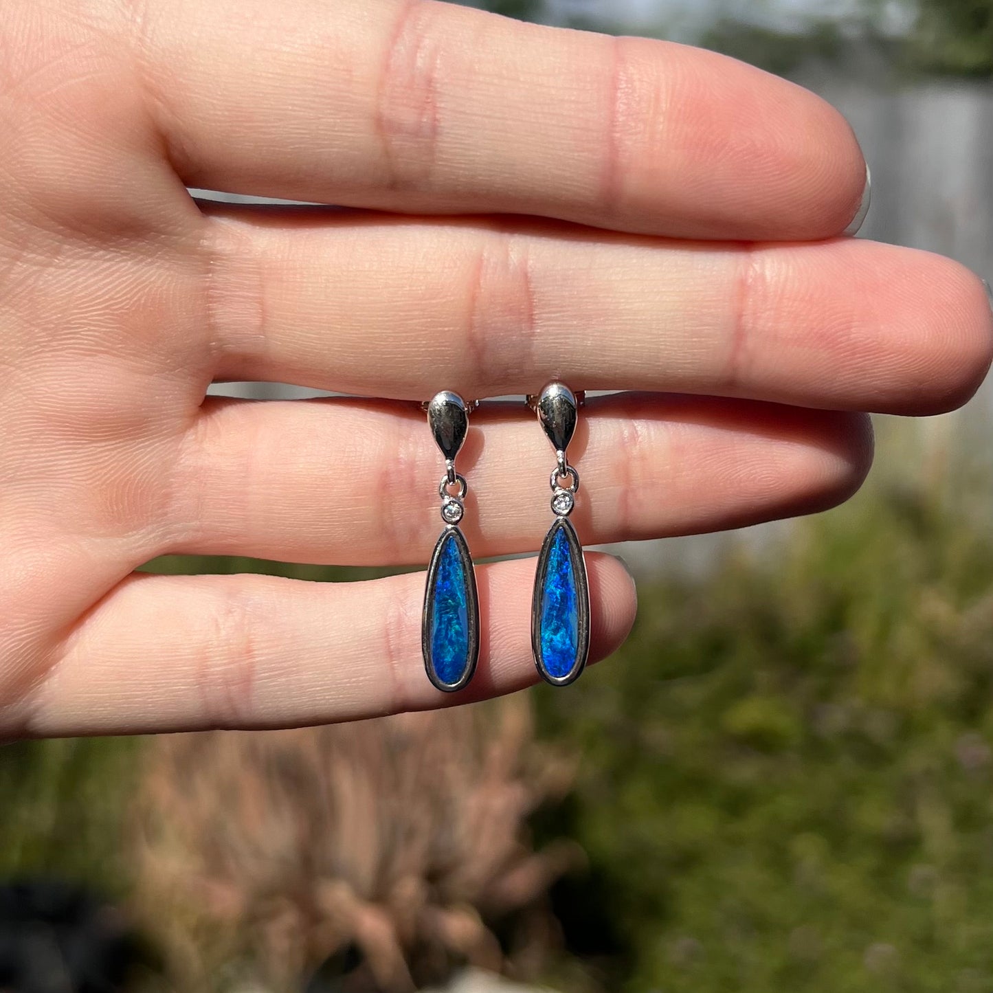 A pair of sterling silver dangle earrings mounted with pear shaped black opal doublets.