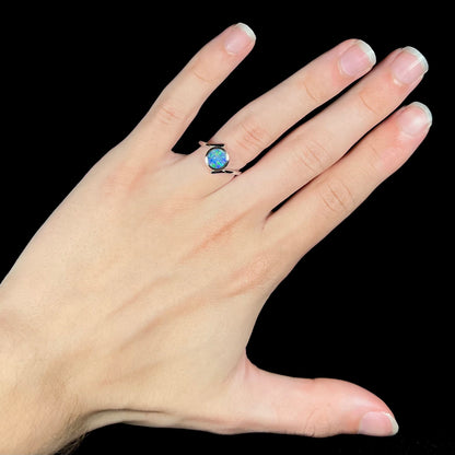 A sterling silver bypass ring bezel-set with a round cut black opal doublet.