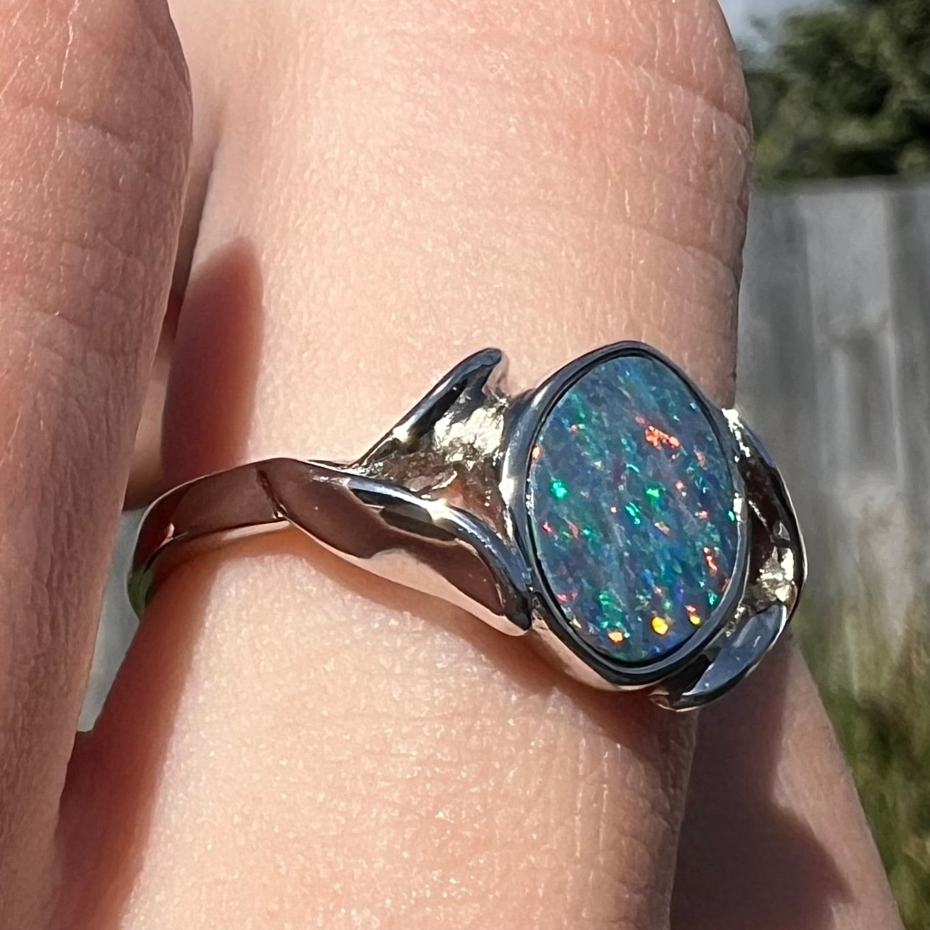 A silver leaf-style ring mounted with a multicolor black opal doublet.