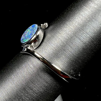 A sterling silver bypass ring bezel-set with a round cut black opal doublet.