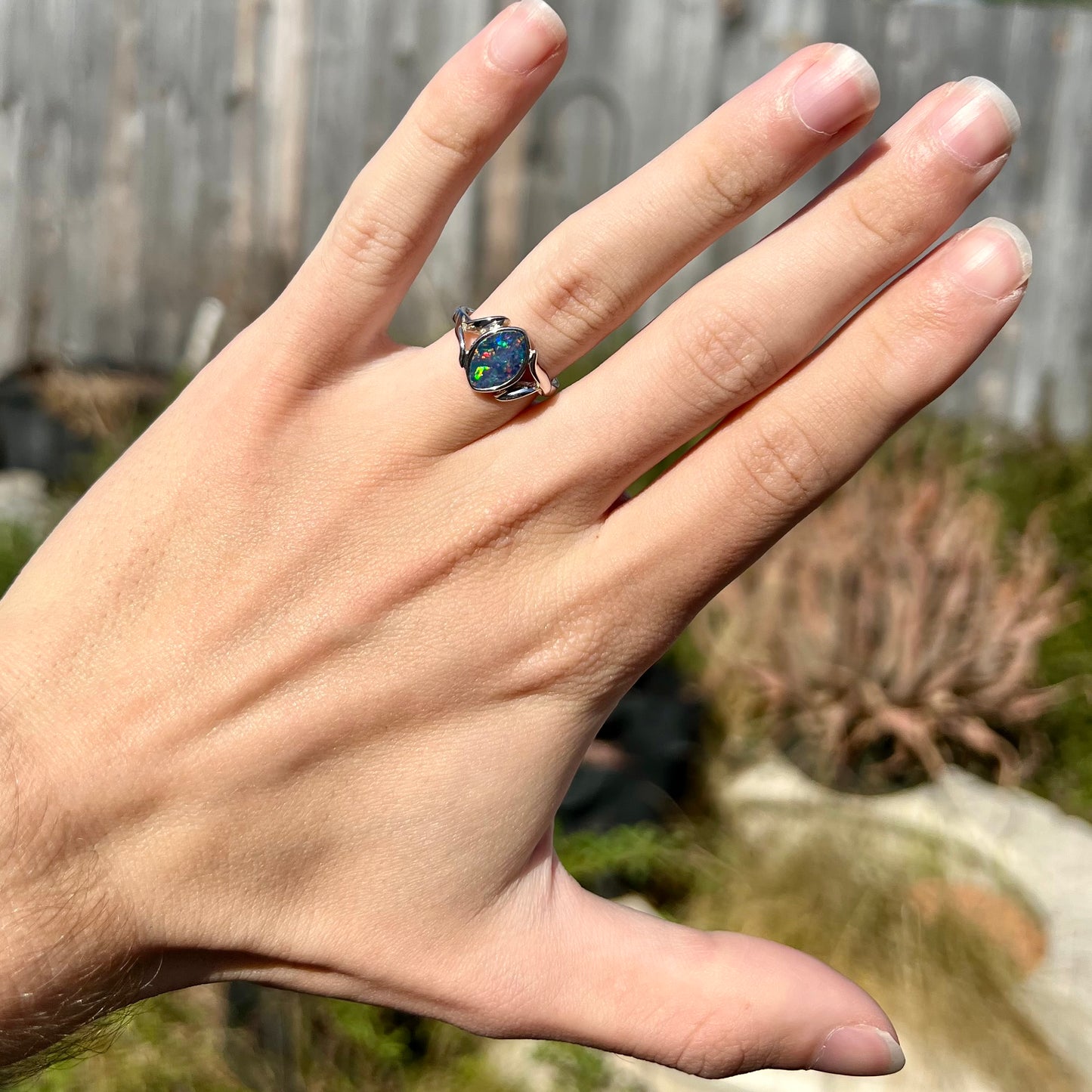 A sterling silver ring mounted with a marquise cut black opal doublet.  The opal has red fire.