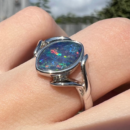 A sterling silver ring mounted with a marquise cut black opal doublet.  The opal has red fire.