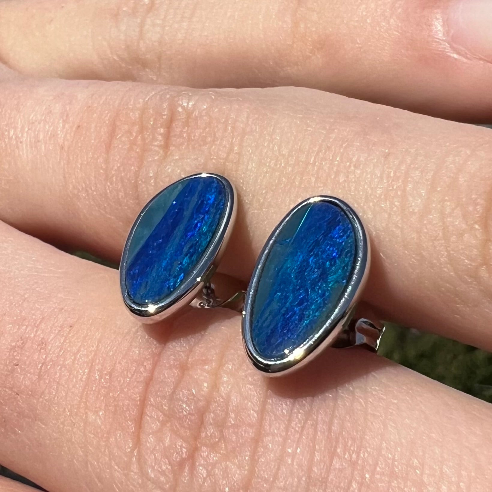 A pair of sterling silver opal doublet stud earrings.  The opals have a vivid blue color.