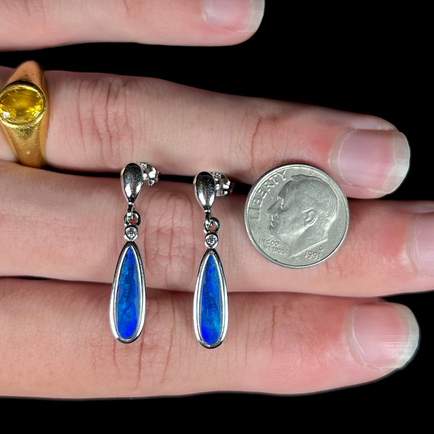 A pair of sterling silver dangle earrings mounted with pear shaped black opal doublets.