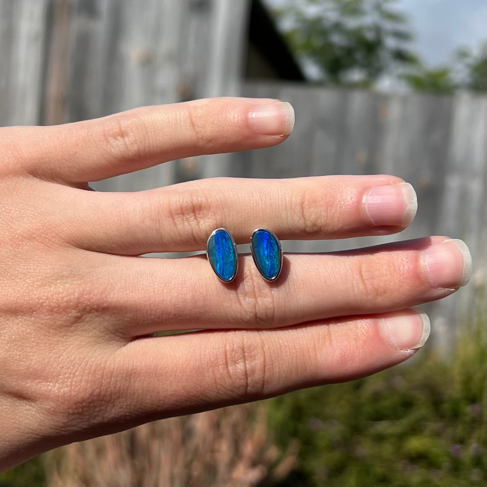 A pair of sterling silver opal doublet stud earrings.  The opals have a vivid blue color.