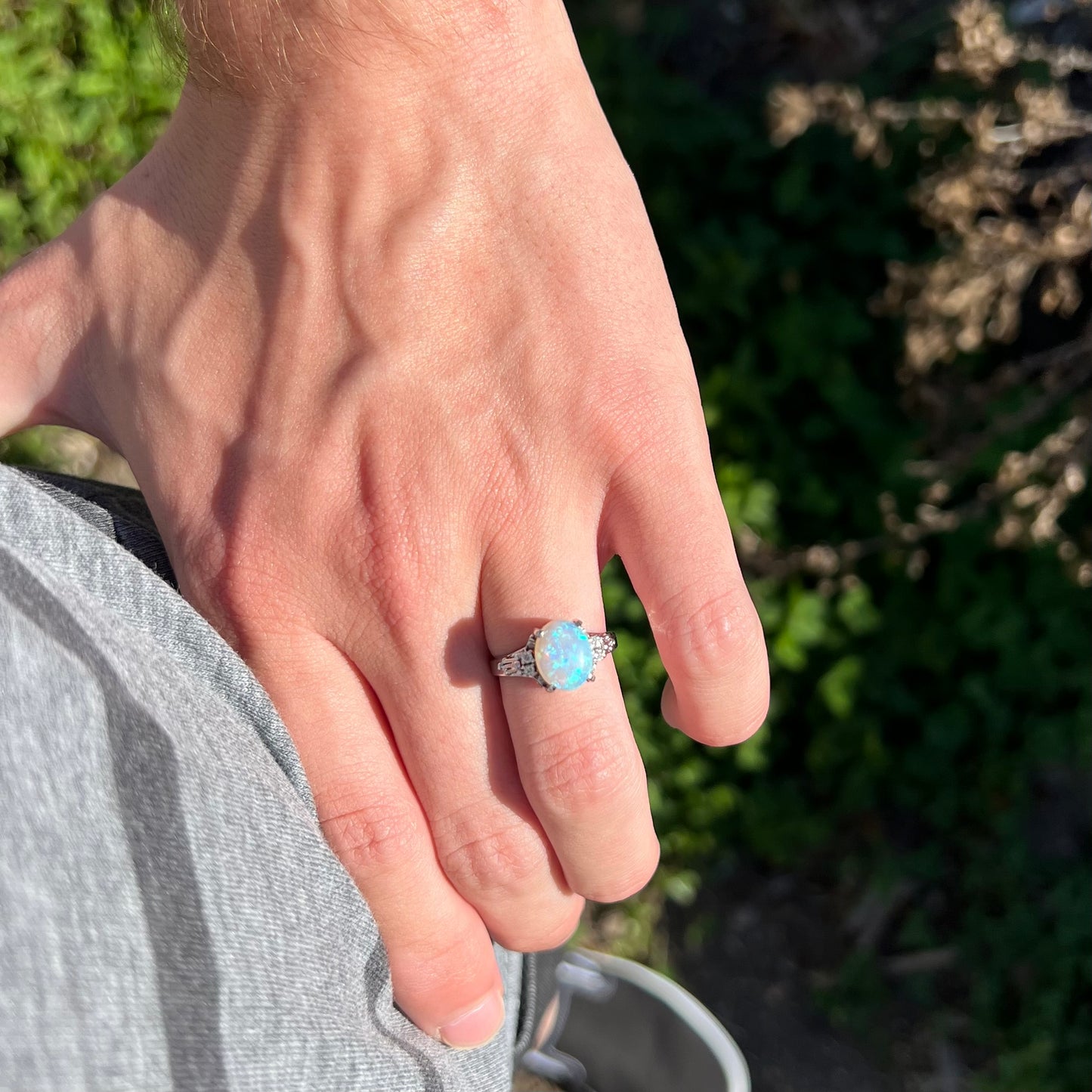 A platinum filigree ring mounted with a blue-green crystal opal and diamond accents.