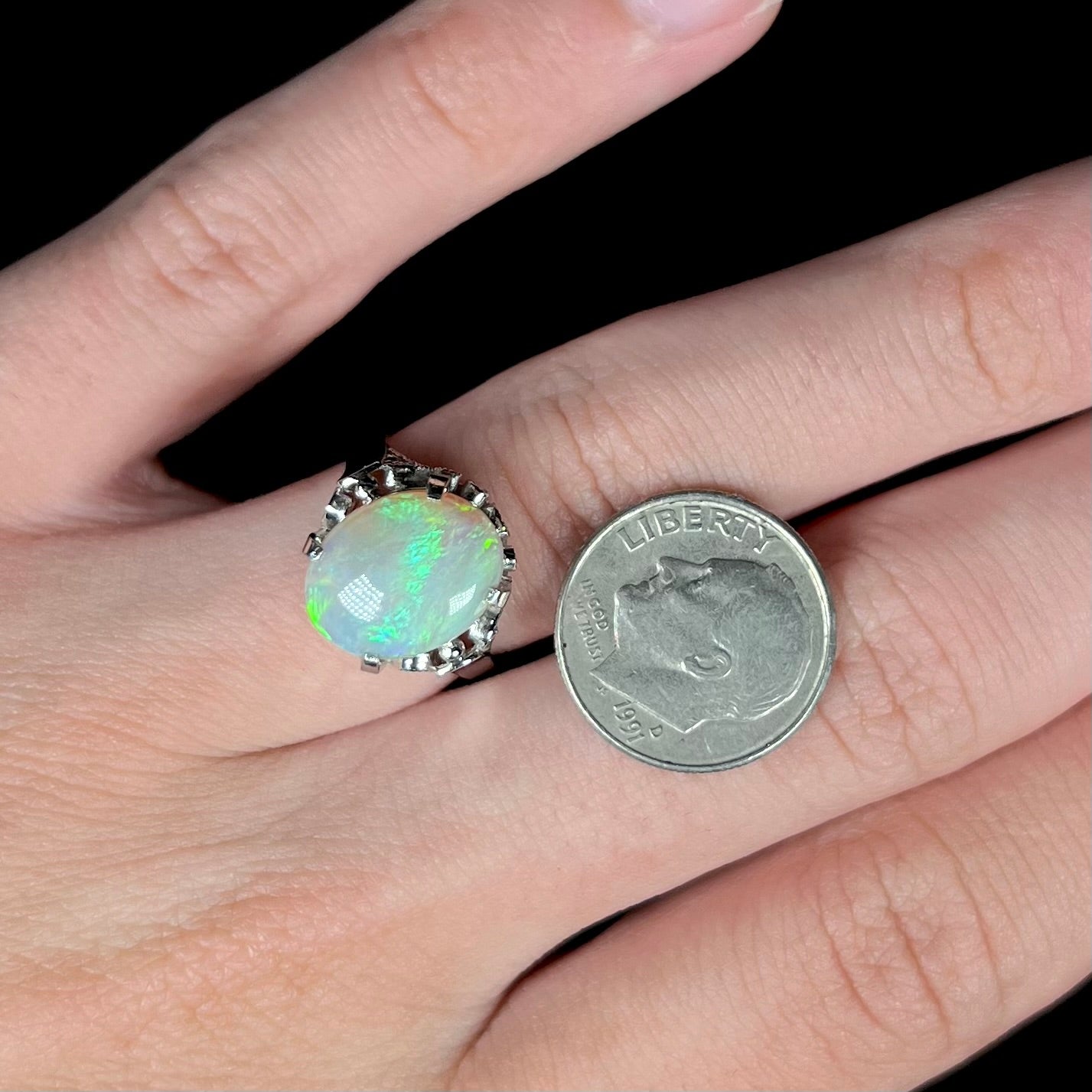 A ladies' Australian opal solitaire engagement ring mounted in platinum.  The opal has green and blue colors.