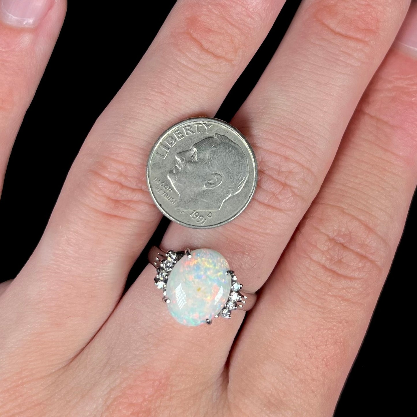 An Australian opal and diamond engagement ring in platinum.  The ring has filigree scrolling.