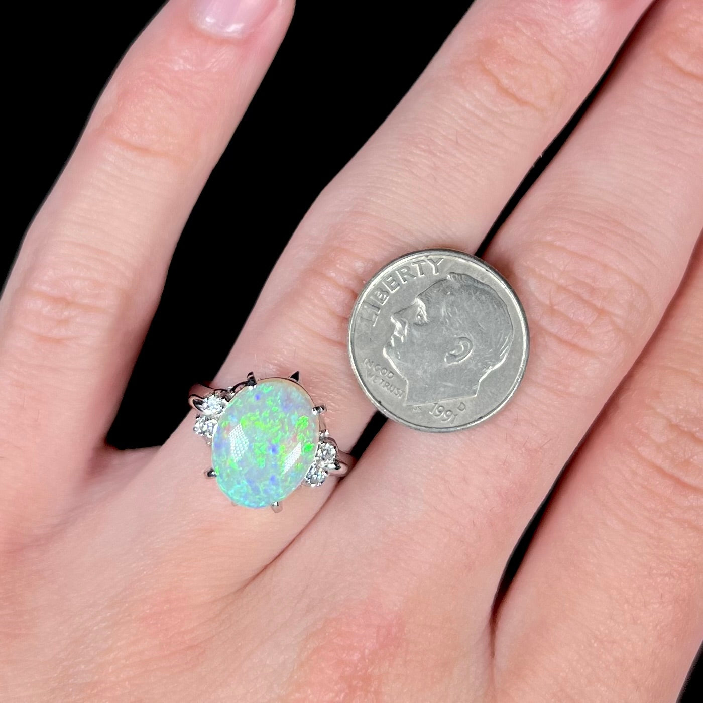 An Australian crystal opal and diamond engagement ring set in a platinum filigree mounting.  The opal plays green/blue colors and has a crack.