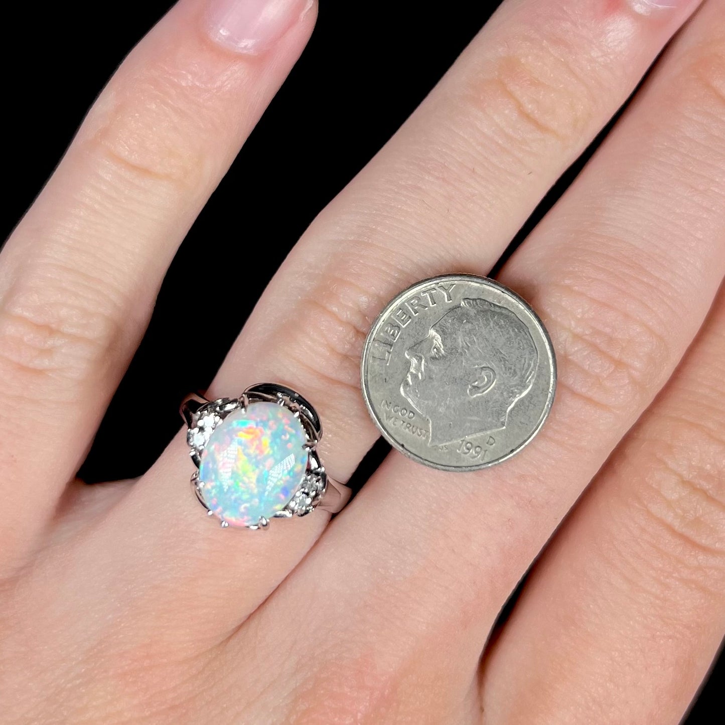 A platinum  and diamond ring prong-set with an Australian opal.  The opal has pink color play.