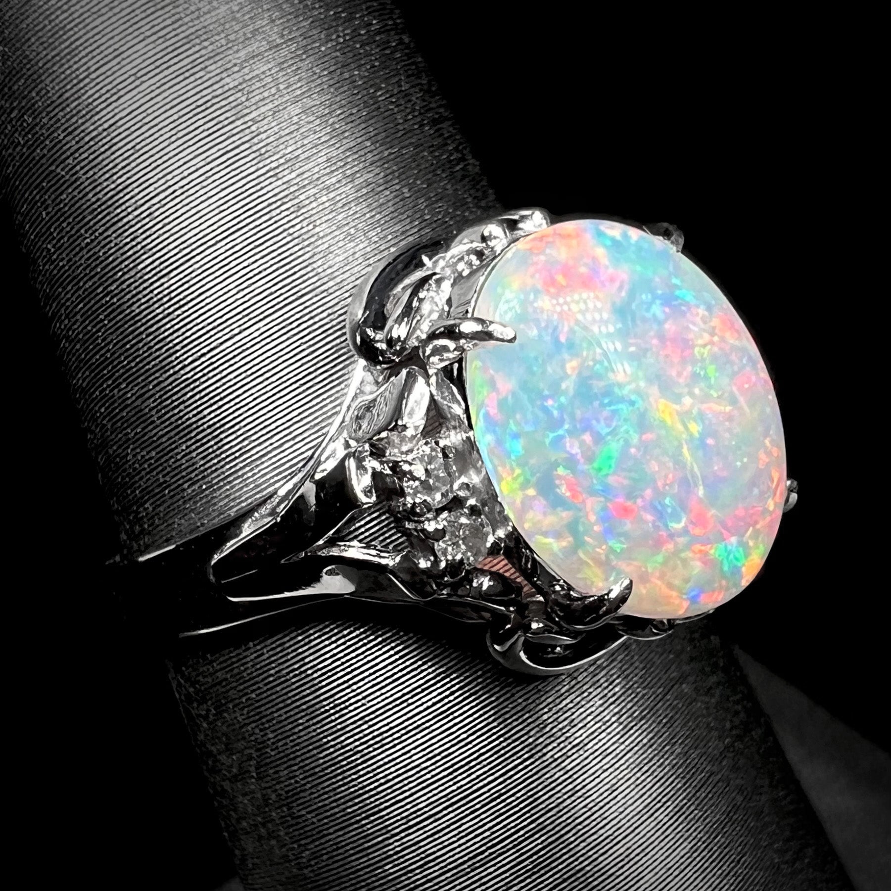 A platinum  and diamond ring prong-set with an Australian opal.  The opal has pink color play.