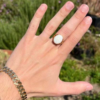 A yellow gold solitaire cocktail ring mounted with a natural white opal from Coober Pedy, Australia.