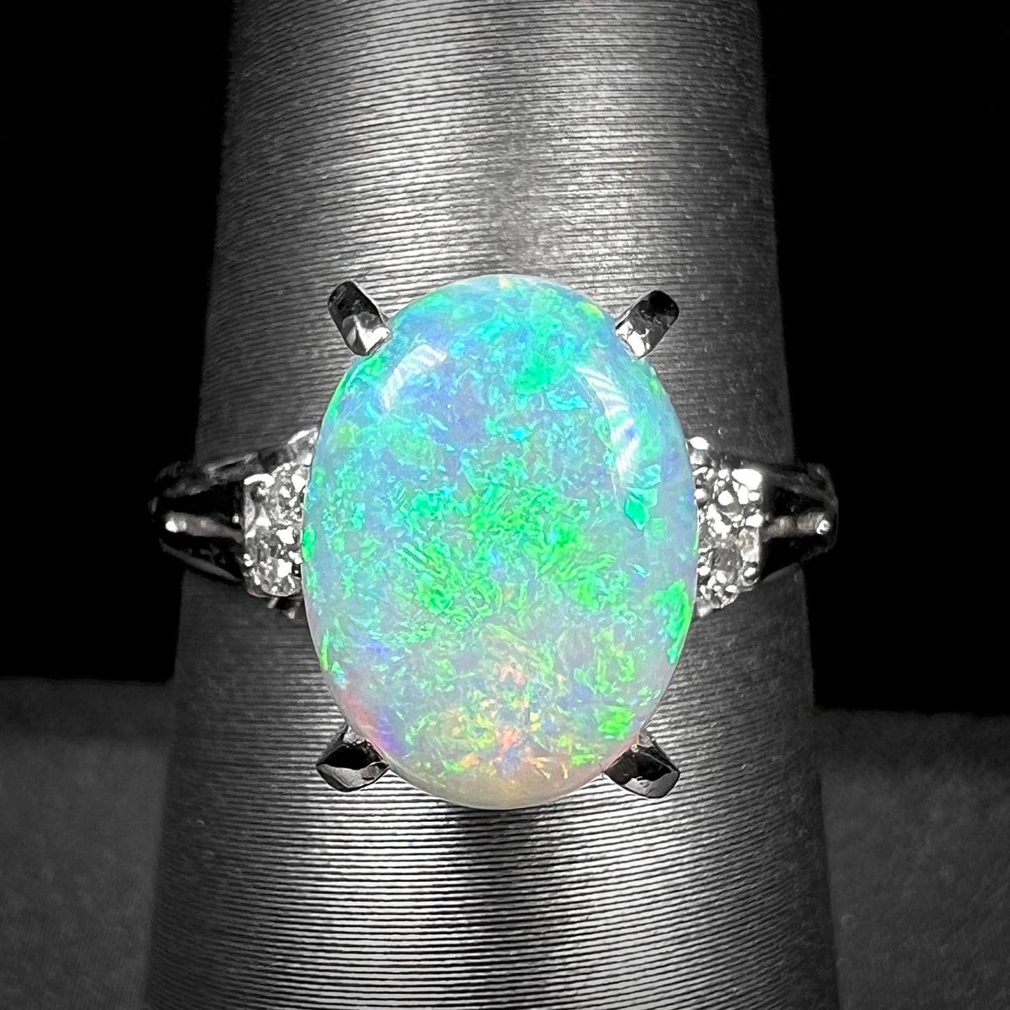 A platinum filigree opal engagement ring set with diamond accents.  The opal has green-blue colors.