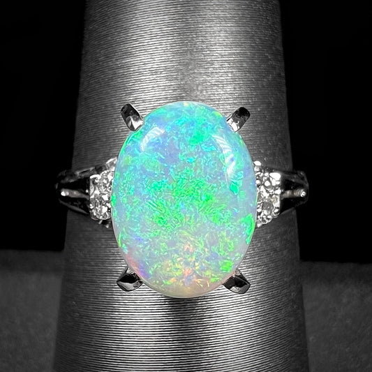 A platinum filigree opal engagement ring set with diamond accents.  The opal has green-blue colors.