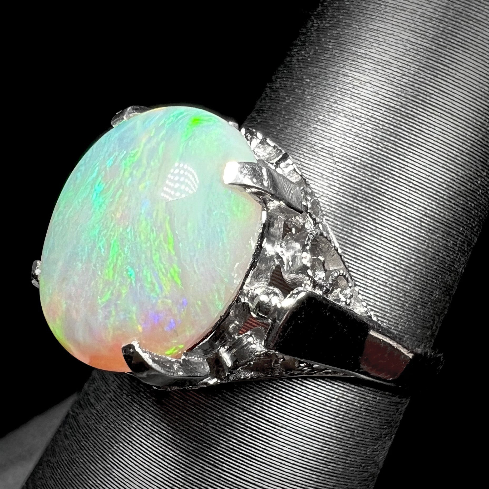 A ladies' Australian opal solitaire engagement ring mounted in platinum.  The opal has green and blue colors.