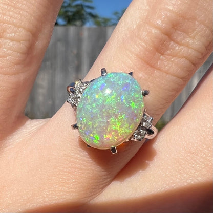 An Australian crystal opal engagement ring set with diamonds in a platinum filigree mounting.  The opal plays green/blue colors and has a crack.