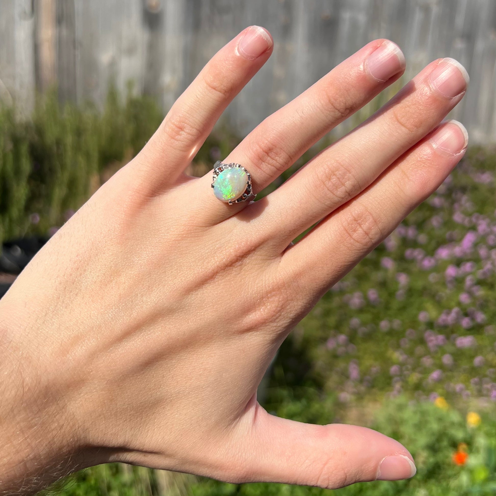 A ladies' Australian opal solitaire engagement ring mounted in platinum.  The opal has green and blue colors.