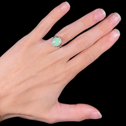 A ladies' Australian opal solitaire engagement ring mounted in platinum.  The opal has green and blue colors.