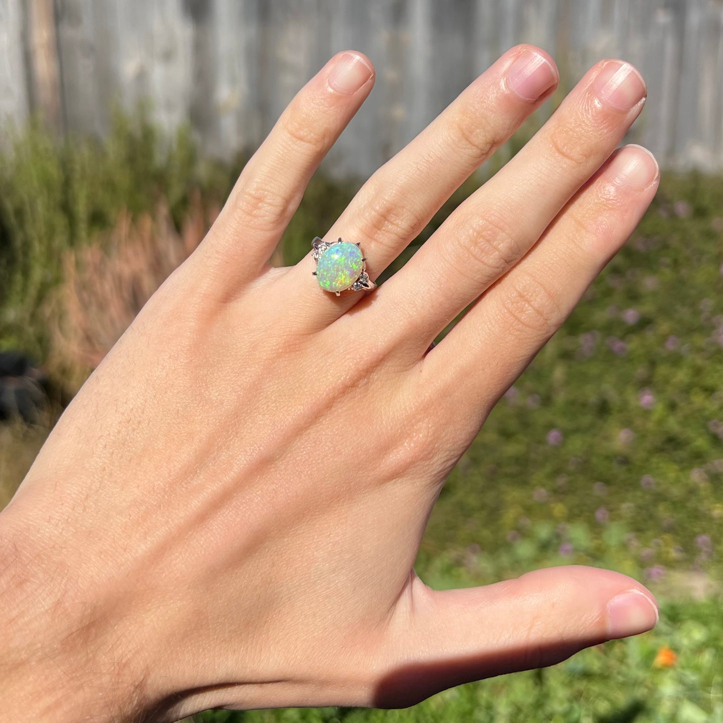 An Australian crystal opal and diamond engagement ring set in a platinum filigree mounting.  The opal plays green/blue colors and has a crack.