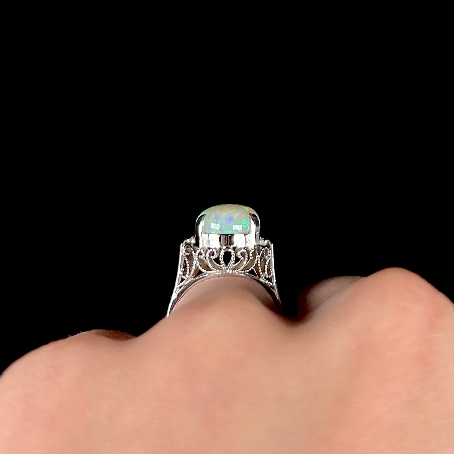 A ladies' Australian opal solitaire engagement ring mounted in platinum.  The opal has green and blue colors.