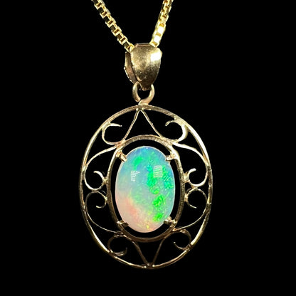 An 18 karat yellow gold filigree opal necklace.  The opal has bright green color play.