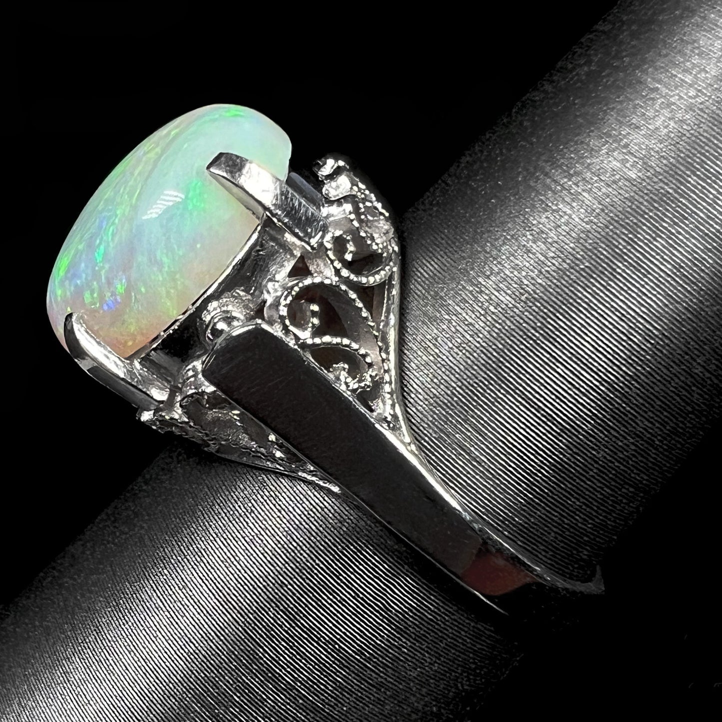 A ladies' Australian opal solitaire engagement ring mounted in platinum.  The opal has green and blue colors.