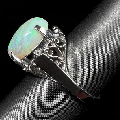 A ladies' Australian opal solitaire engagement ring mounted in platinum.  The opal has green and blue colors.