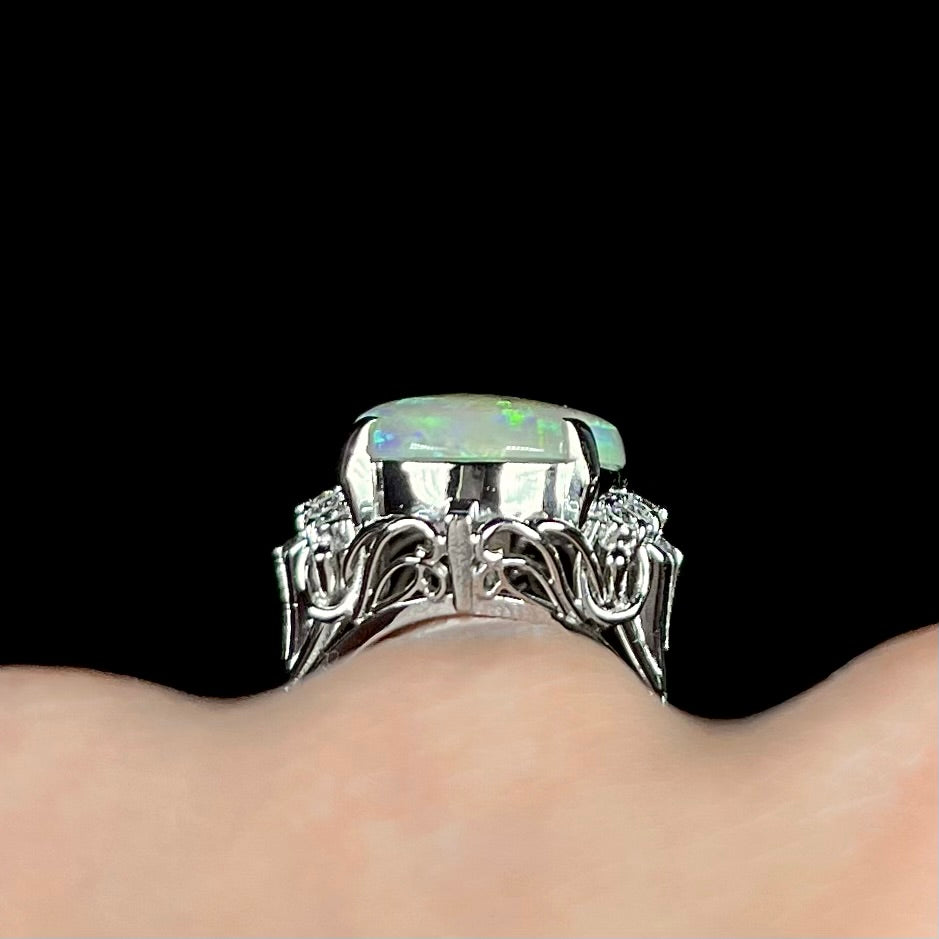 A platinum filigree ring set with a large, green-blue Mintabie crystal opal and diamonds.