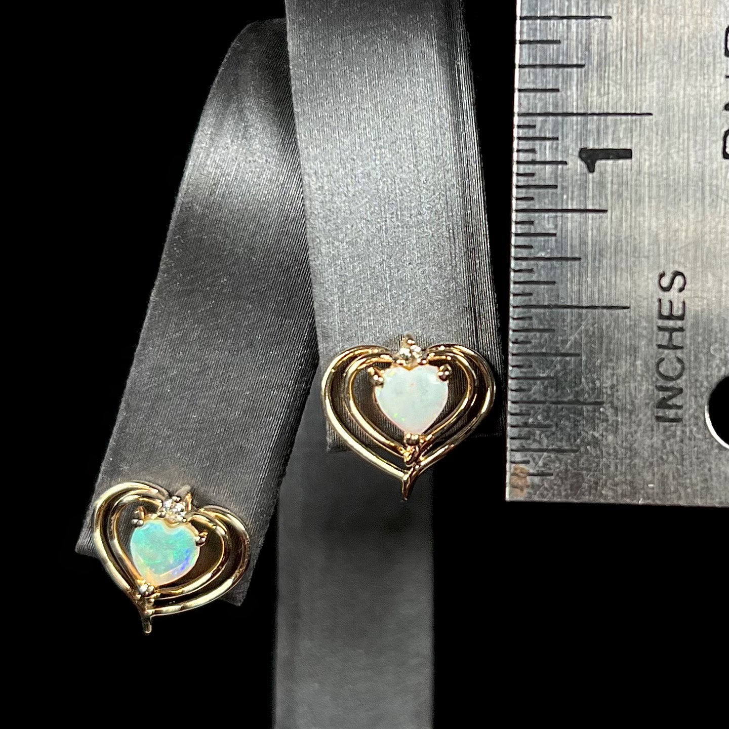 A pair of heart shaped, yellow gold opal stud earrings.  The top of the earrings have a diamond accent.