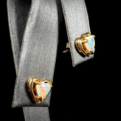 A pair of yellow gold stud earrings mounted with heart shaped natural crystal opals.