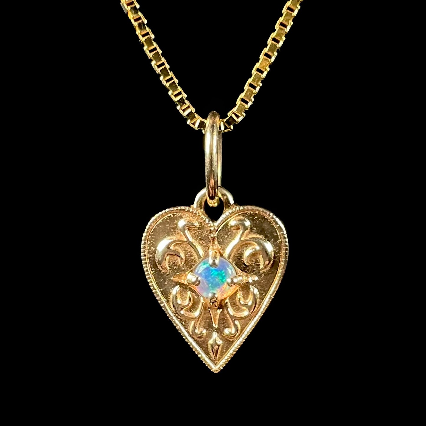 A yellow gold filigree heart necklace set with a round Australian crystal opal.  The opal has green fire.