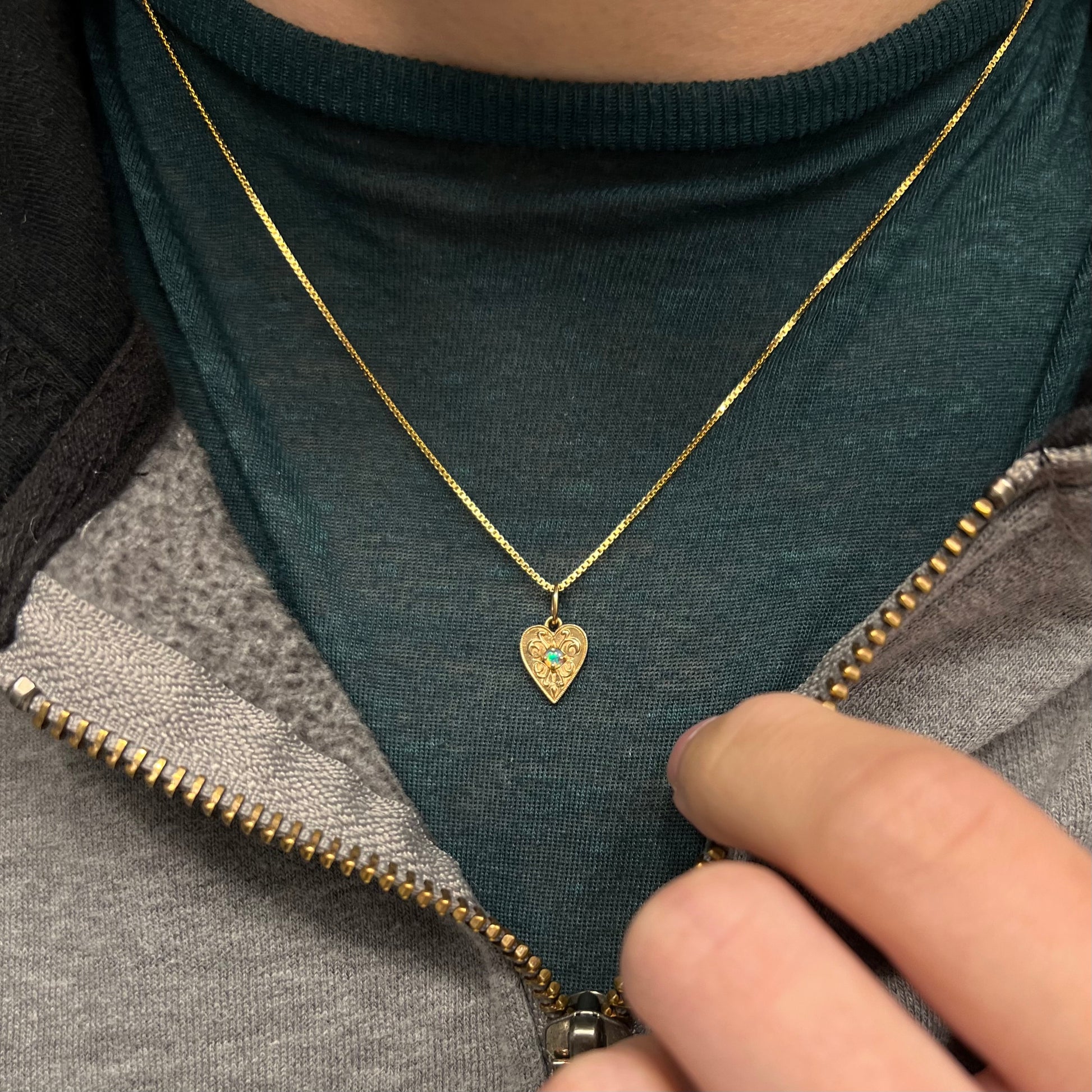 A yellow gold filigree heart necklace set with a round Australian crystal opal.  The opal has green fire.