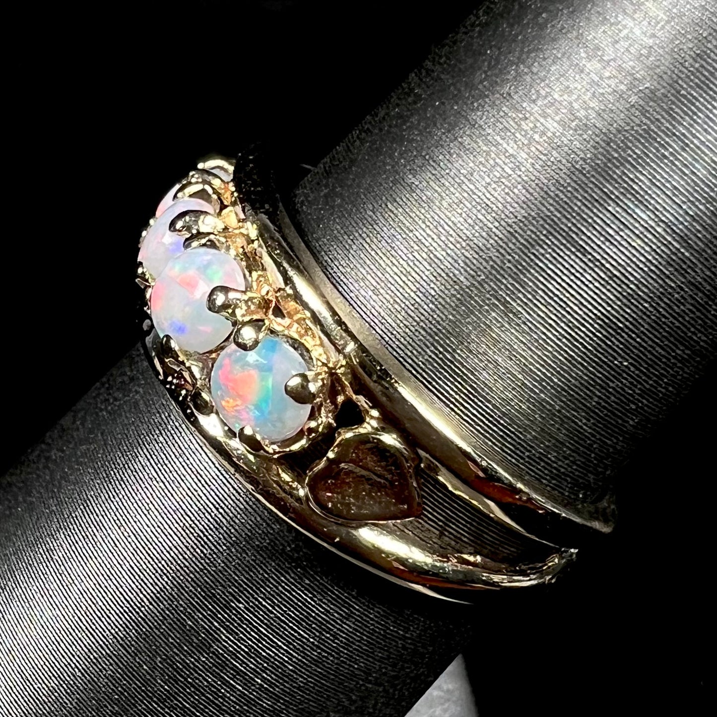 A yellow gold band set with five round cabochon cut opals and heart design accents.