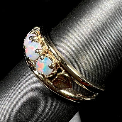 A yellow gold band set with five round cabochon cut opals and heart design accents.